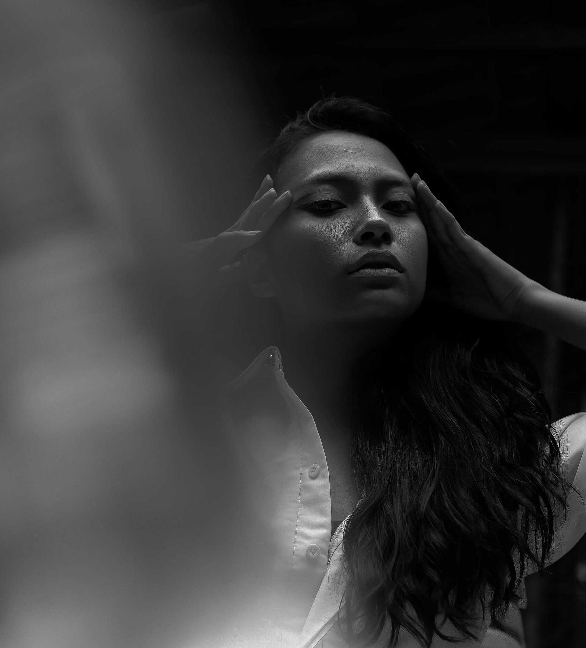 Black and white photo of a woman holding her head, conveying emotion or contemplation.